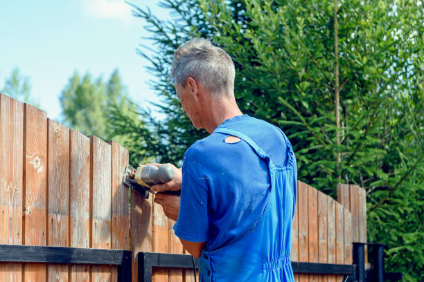 person using an electric tool to build a wooden fence